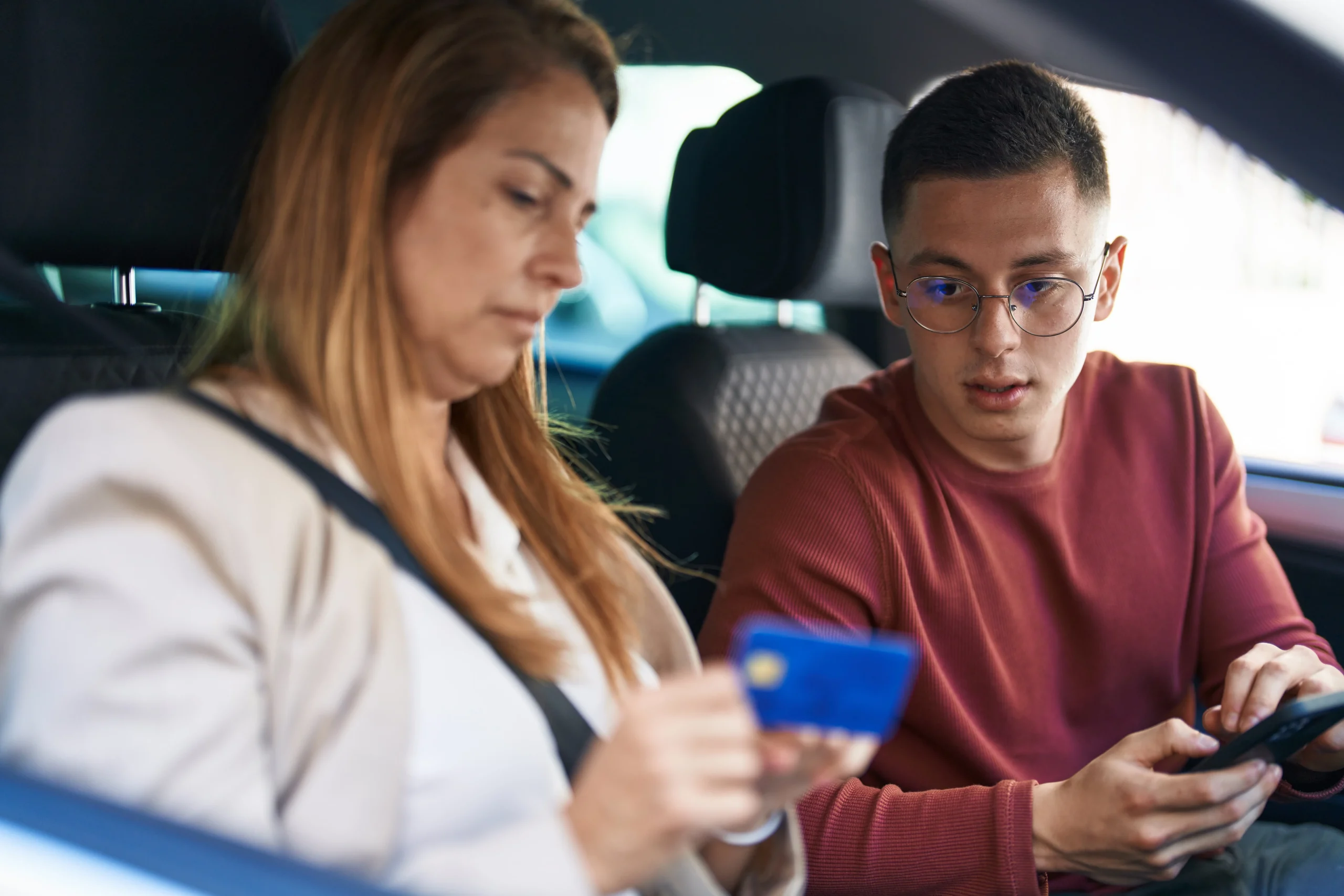 man-woman-mother-son-using-smartphone-credit-card-sitting-car-street-scaled